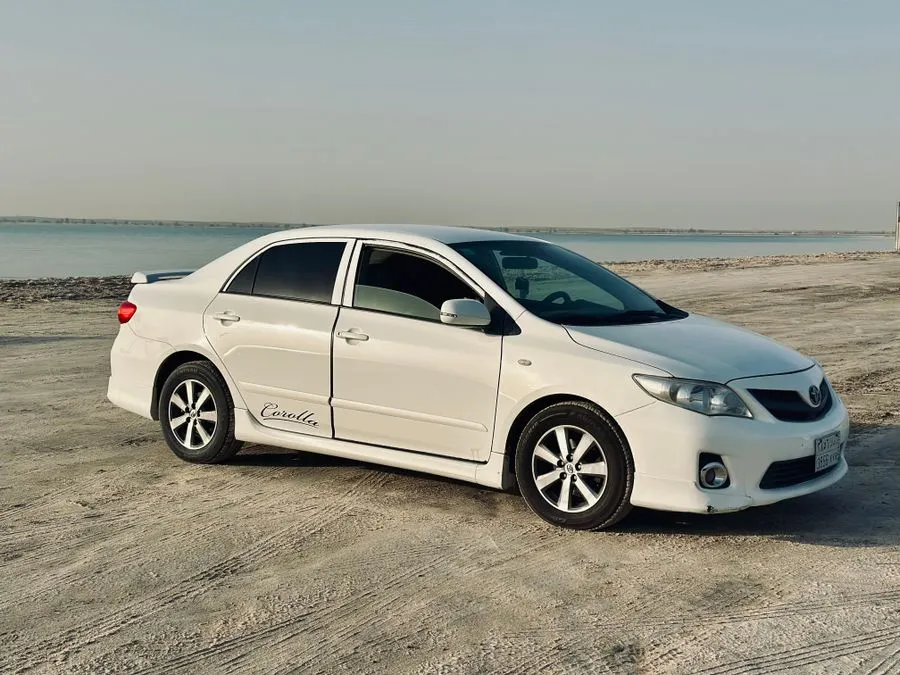 White Toyota Corolla parked on a sandy beach